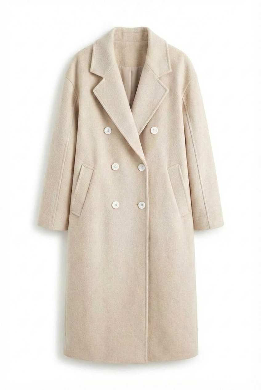 Beige - A woman wearing a camel-coloured, double-breasted longline coat with notch lapels and folded cuffs, styled over a striped sweater, blue jeans, and black boots against a white background.
