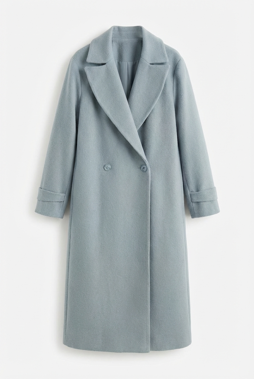 Blue - A woman wearing a camel-coloured, double-breasted longline coat with notch lapels and folded cuffs, styled over a striped sweater, blue jeans, and black boots against a white background.
