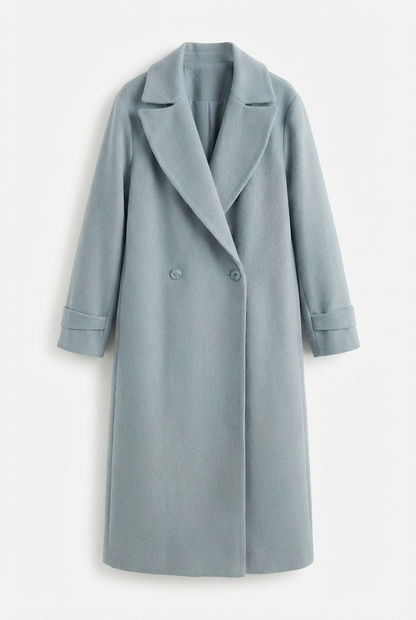Blue - A woman wearing a camel-coloured, double-breasted longline coat with notch lapels and folded cuffs, styled over a striped sweater, blue jeans, and black boots against a white background.