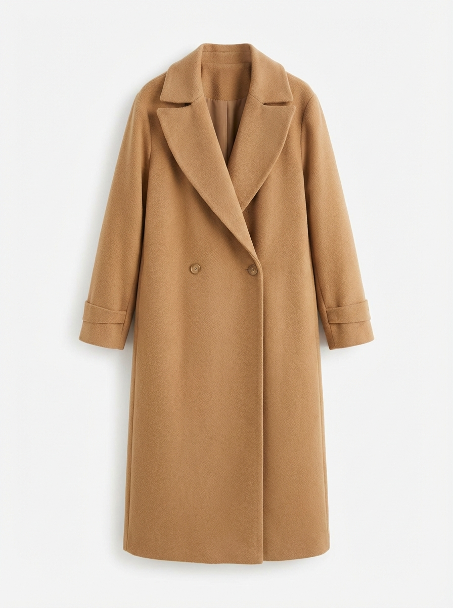 Brown - A woman wearing a camel-coloured, double-breasted longline coat with notch lapels and folded cuffs, styled over a striped sweater, blue jeans, and black boots against a white background.