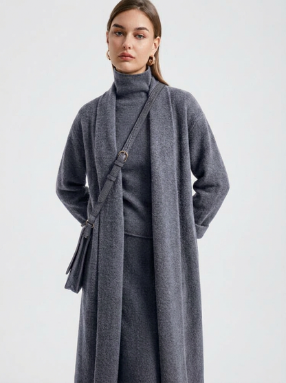A woman wearing a grey brushed knit longline cardigan with a matching turtleneck and skirt, showcasing a minimalist, monochromatic look.