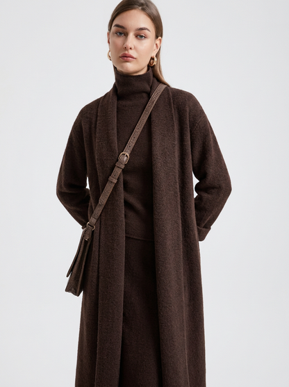 A woman wearing a grey brushed knit longline cardigan with a matching turtleneck and skirt, showcasing a minimalist, monochromatic look.