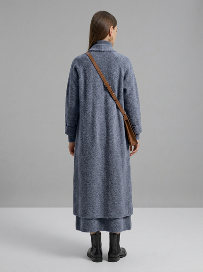 A woman wearing a grey brushed knit longline cardigan with a matching turtleneck and skirt, showcasing a minimalist, monochromatic look.