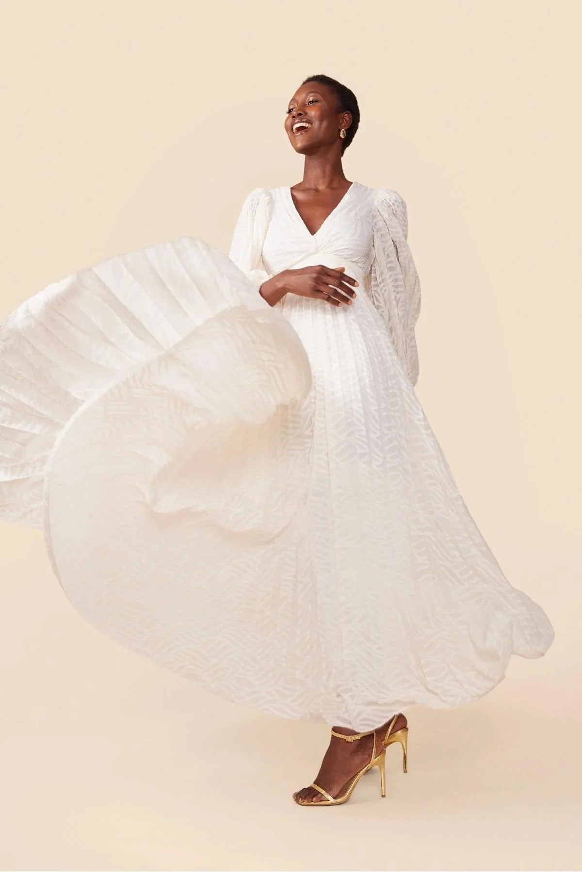 WHite - A woman stands outdoors near a pond wearing a long, flowing white maxi dress with a deep V-neck, ruched bodice, voluminous long sleeves, and an intricate burnout texture pattern.