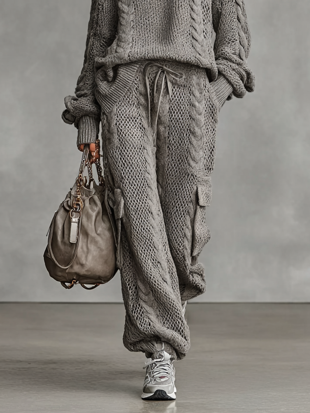 Gray - A woman wearing a matching grey cable knit two-piece set featuring a roll neck jumper and relaxed-fit cargo trousers with a drawstring waist.