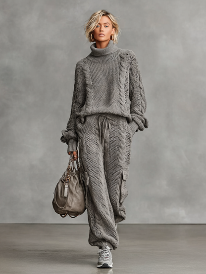 Gray - A woman wearing a matching grey cable knit two-piece set featuring a roll neck jumper and relaxed-fit cargo trousers with a drawstring waist.