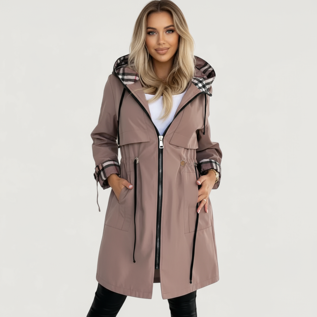 Brown - A woman wearing a taupe mid-length hooded jacket with a black zip front, featuring a distinctive black, white, and red check lining visible in the hood and rolled cuffs.