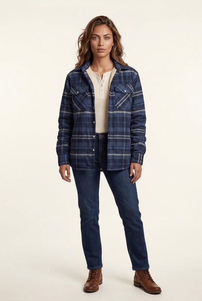 Navy Blue - A woman wearing a brown plaid flannel shirt jacket with a cream shearling lining, paired with dark wash jeans and brown leather boots.
