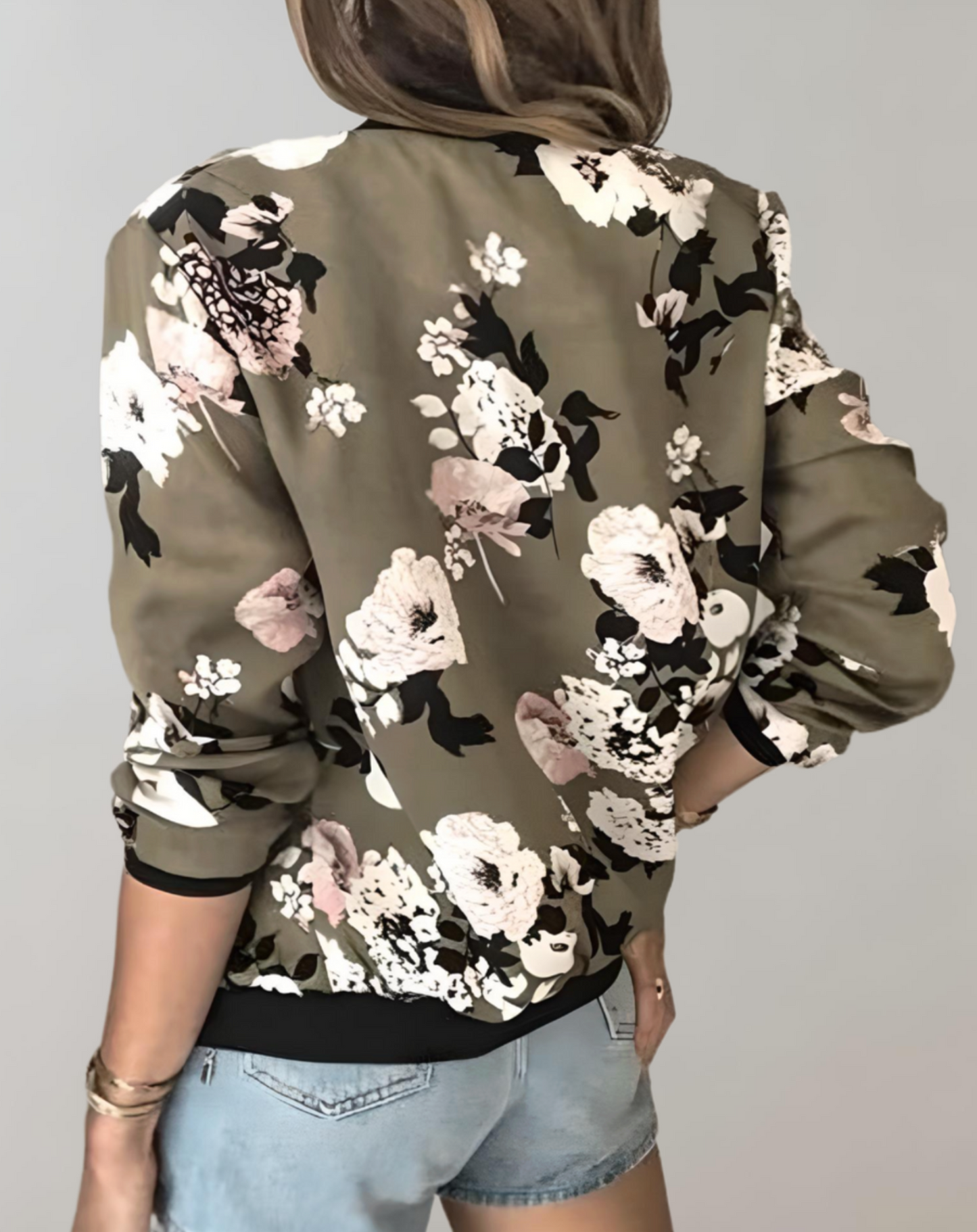Blue - A woman wearing a white bomber jacket featuring a detailed pink cherry blossom and green leaf print, styled with black pants against a neutral grey background.