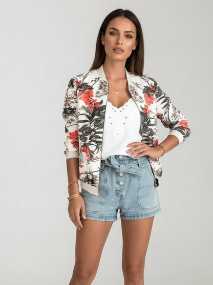 Orange - A woman wearing a white bomber jacket featuring a detailed pink cherry blossom and green leaf print, styled with black pants against a neutral grey background.