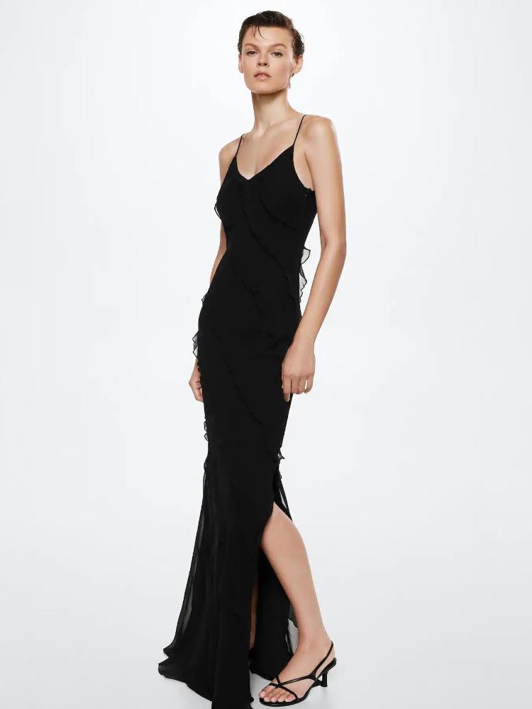 Red - A woman wearing a vibrant red chiffon maxi dress with cascading diagonal ruffles, a V-neckline, and thin spaghetti straps, posing against a rustic dark wooden door.