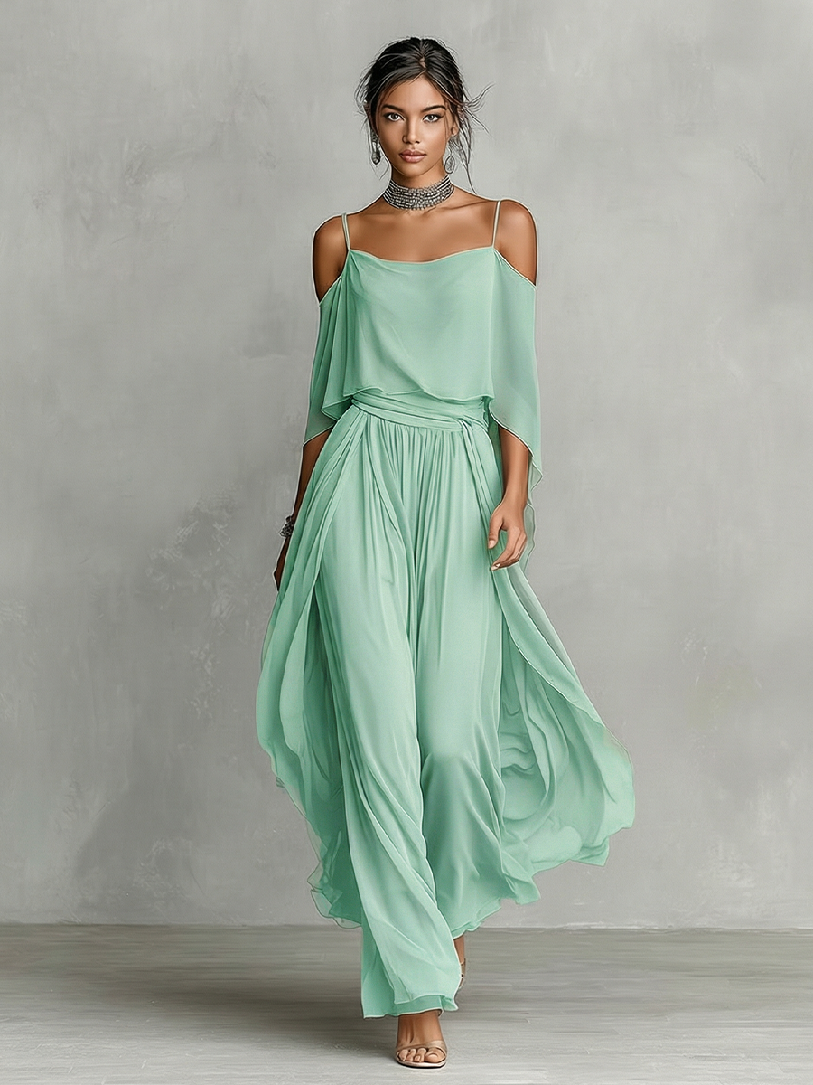 Green - A model wears a floor-length grey chiffon maxi dress featuring delicate spaghetti straps, a draped cold-shoulder overlay, a ruched waist, and a layered, flowing skirt.