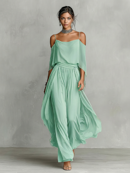 Green - A model wears a floor-length grey chiffon maxi dress featuring delicate spaghetti straps, a draped cold-shoulder overlay, a ruched waist, and a layered, flowing skirt.