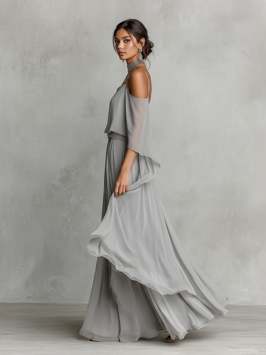 Green - A model wears a floor-length grey chiffon maxi dress featuring delicate spaghetti straps, a draped cold-shoulder overlay, a ruched waist, and a layered, flowing skirt.