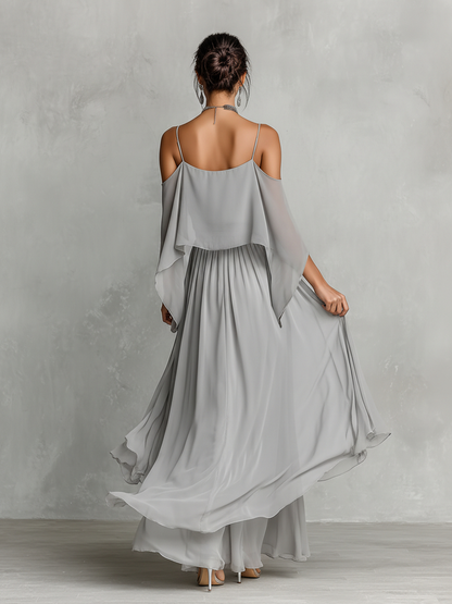 Green - A model wears a floor-length grey chiffon maxi dress featuring delicate spaghetti straps, a draped cold-shoulder overlay, a ruched waist, and a layered, flowing skirt.