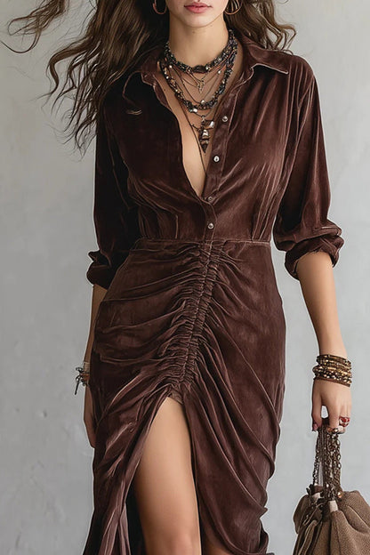 Brown - Woman walking wearing a long velvet dress with a collared neckline, button front, center ruching, and a high front slit, styled with tall western boots.