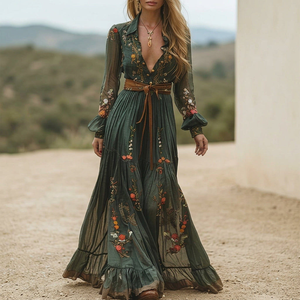 Green - A woman wearing a dark green embroidered chiffon maxi dress with long balloon sleeves, a collared deep V-neckline, and a tiered pleated skirt, accessorised with a brown tie belt.