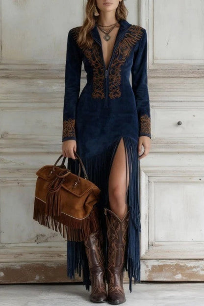 Navy - Woman wearing a long-sleeve maxi dress with intricate chest embroidery, an adjustable zip-front neckline, and a dramatic floor-length fringed skirt with a high leg slit, styled with western boots.