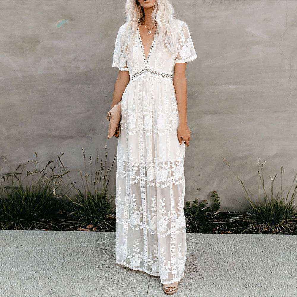 Women's resort maxi dress featuring a deep V-neckline, short flutter sleeves, and intricate floral lace embroidery on a sheer overlay with a partial lining.