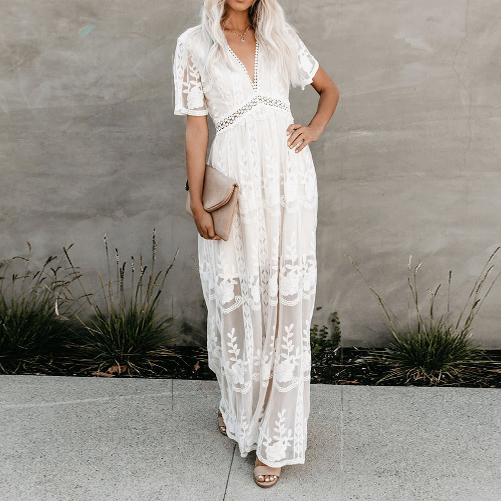 Women's resort maxi dress featuring a deep V-neckline, short flutter sleeves, and intricate floral lace embroidery on a sheer overlay with a partial lining.