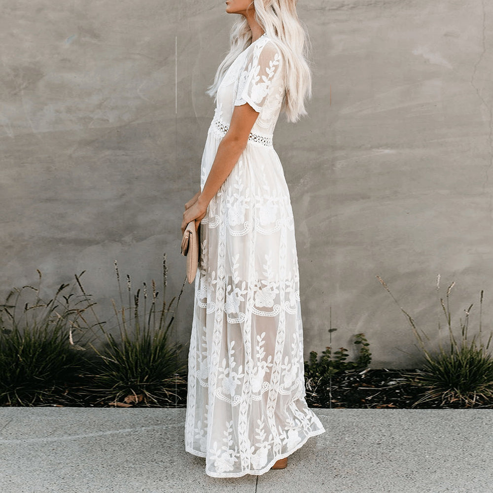 Women's resort maxi dress featuring a deep V-neckline, short flutter sleeves, and intricate floral lace embroidery on a sheer overlay with a partial lining.