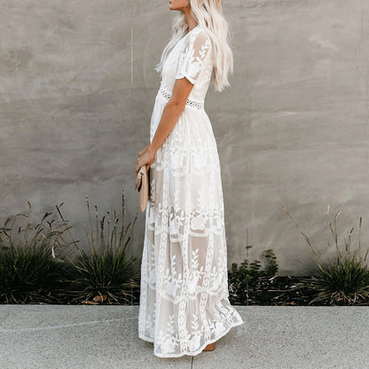 Women's resort maxi dress featuring a deep V-neckline, short flutter sleeves, and intricate floral lace embroidery on a sheer overlay with a partial lining.