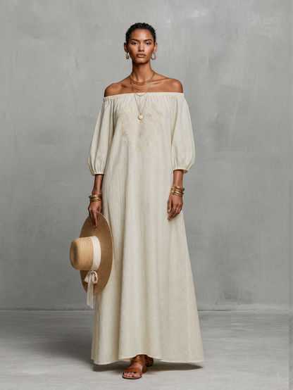 Black - A woman wearing an off-the-shoulder cream linen maxi dress with tonal chest embroidery and puff sleeves, holding a wide-brim straw hat.