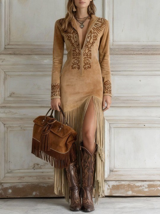 Light brown - A woman wearing a dusty blue long-sleeve maxi dress with brown scroll embroidery on the chest and cuffs, featuring a half-zip front, a high leg slit, and a long fringed hemline.