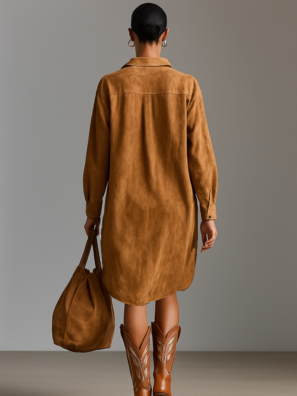 Brown - A model wearing a long-sleeved, ochre-coloured matte satin shift dress featuring a deep V-neckline with intricate floral embroidery, styled with knee-high tan cowboy boots.