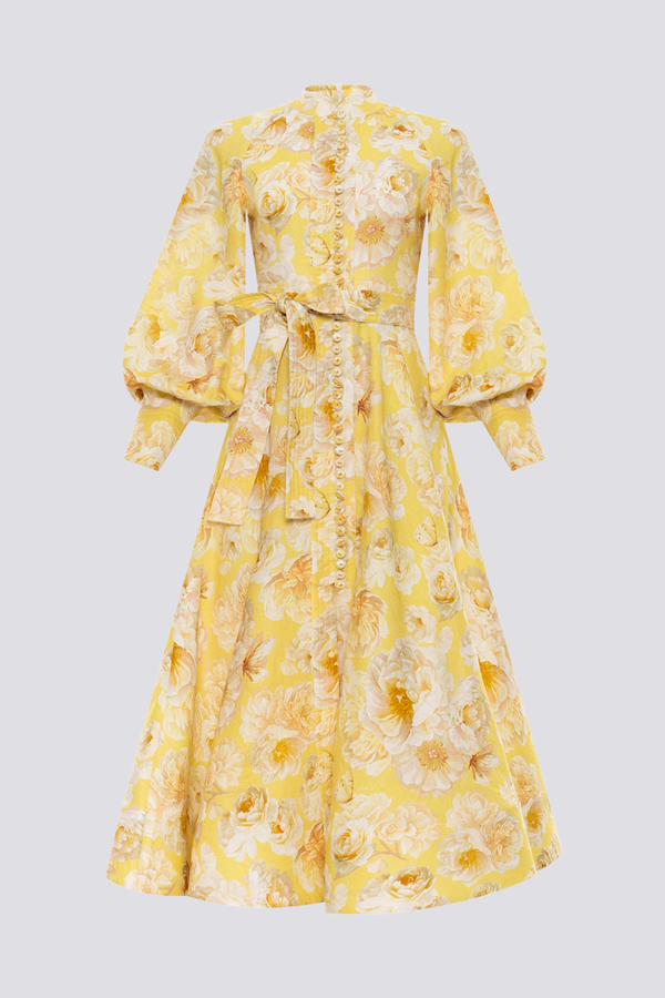 Yellow - A woman wearing a yellow and white floral print maxi dress with long balloon sleeves, a high neckline, button-front detailing, and a self-tie waist.