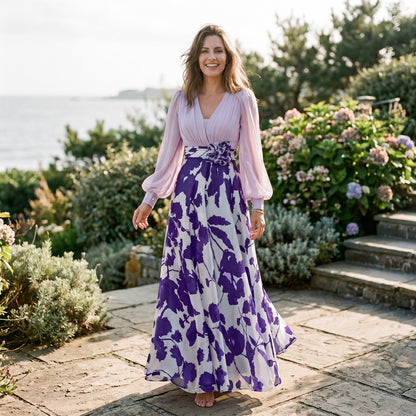 Navy Blue - A woman posing in a floor-length navy and white floral chiffon maxi dress featuring a deep V-neckline, sheer balloon sleeves, and a 3D floral applique at the waist.