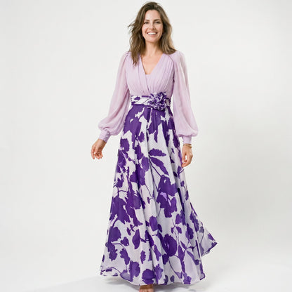 Lilac&Tahiti - A woman posing in a floor-length navy and white floral chiffon maxi dress featuring a deep V-neckline, sheer balloon sleeves, and a 3D floral applique at the waist.