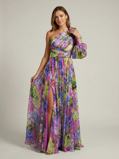 A woman wearing a vibrant floral print chiffon one-shoulder maxi dress with a single long balloon sleeve, ruched bodice, and a high leg slit.