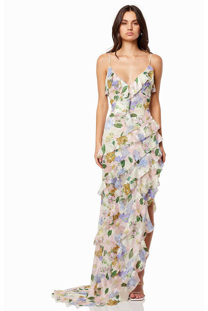 Green - A model wearing a sleeveless maxi dress in a pastel floral print chiffon, featuring cascading ruffles, a V-neckline, and an asymmetric hem with a train.