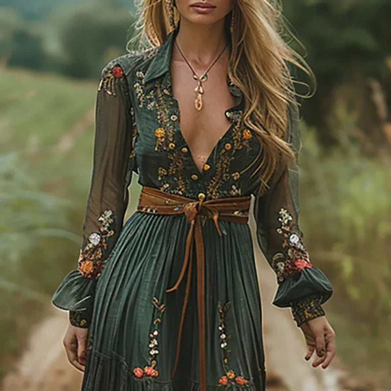 Green (Almost Sold Out) - A woman wearing a long sleeve georgette maxi dress featuring intricate floral embroidery, a button-up front, an adjustable tie waist, and a tiered flowing skirt.