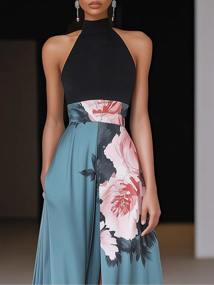 Black - Woman wearing a floor-length maxi dress featuring a solid halter top and a flowing skirt with a large floral placement print and a high front slit.