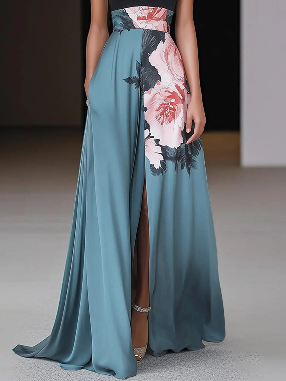 Black - Woman wearing a floor-length maxi dress featuring a solid halter top and a flowing skirt with a large floral placement print and a high front slit.