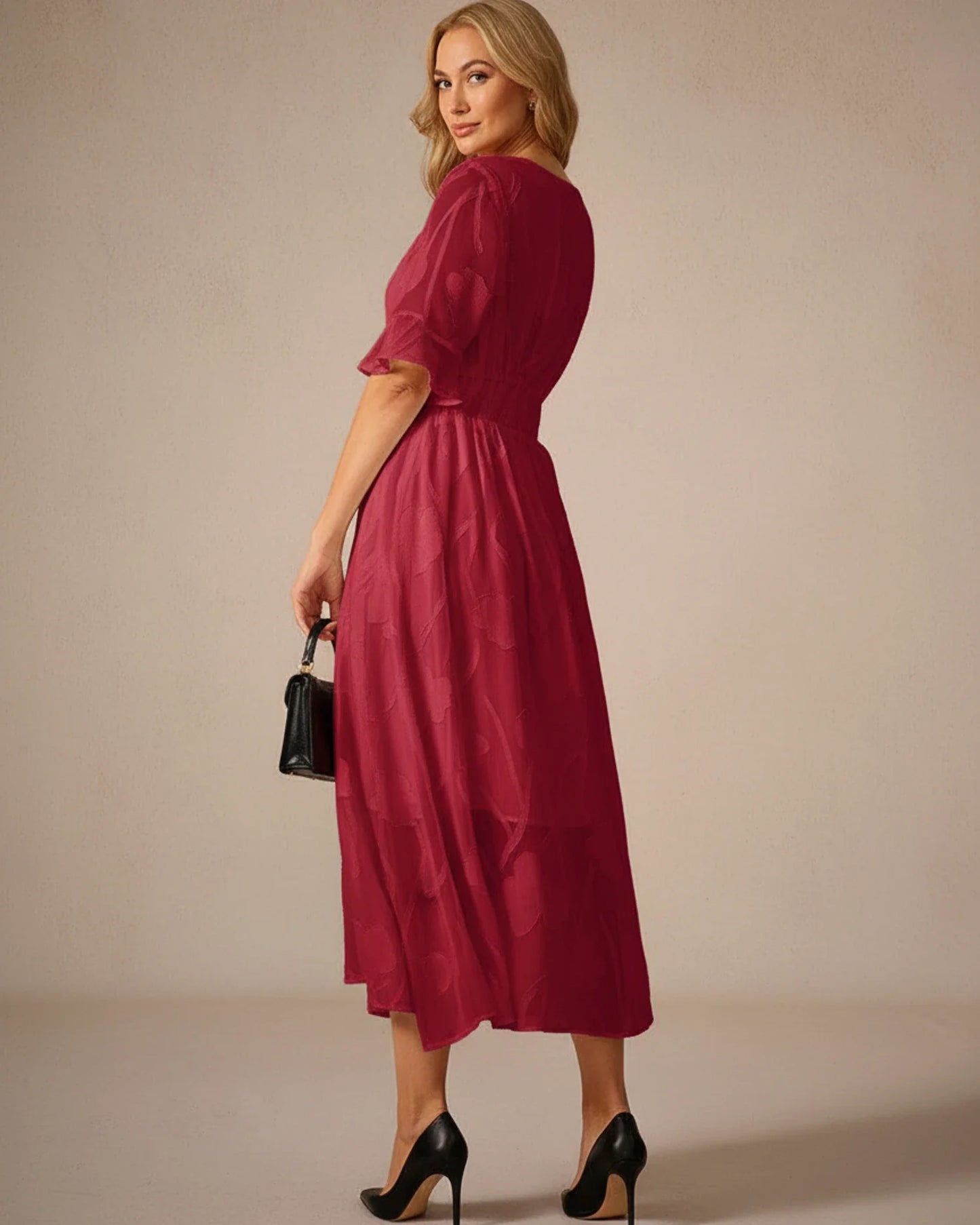 Red - A woman models a black formal midi dress featuring a V-neckline, flutter sleeves, and a textured floral jacquard overlay with a sheer hemline.