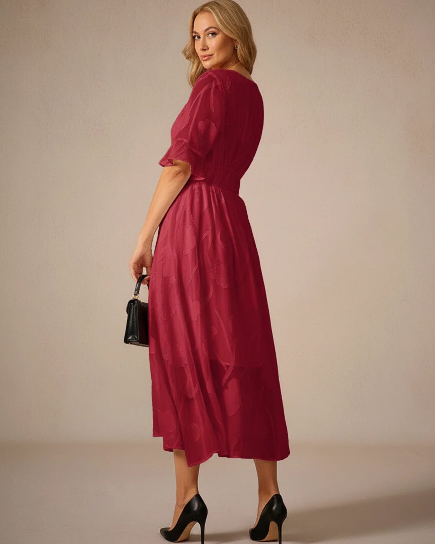 Red - A woman models a black formal midi dress featuring a V-neckline, flutter sleeves, and a textured floral jacquard overlay with a sheer hemline.