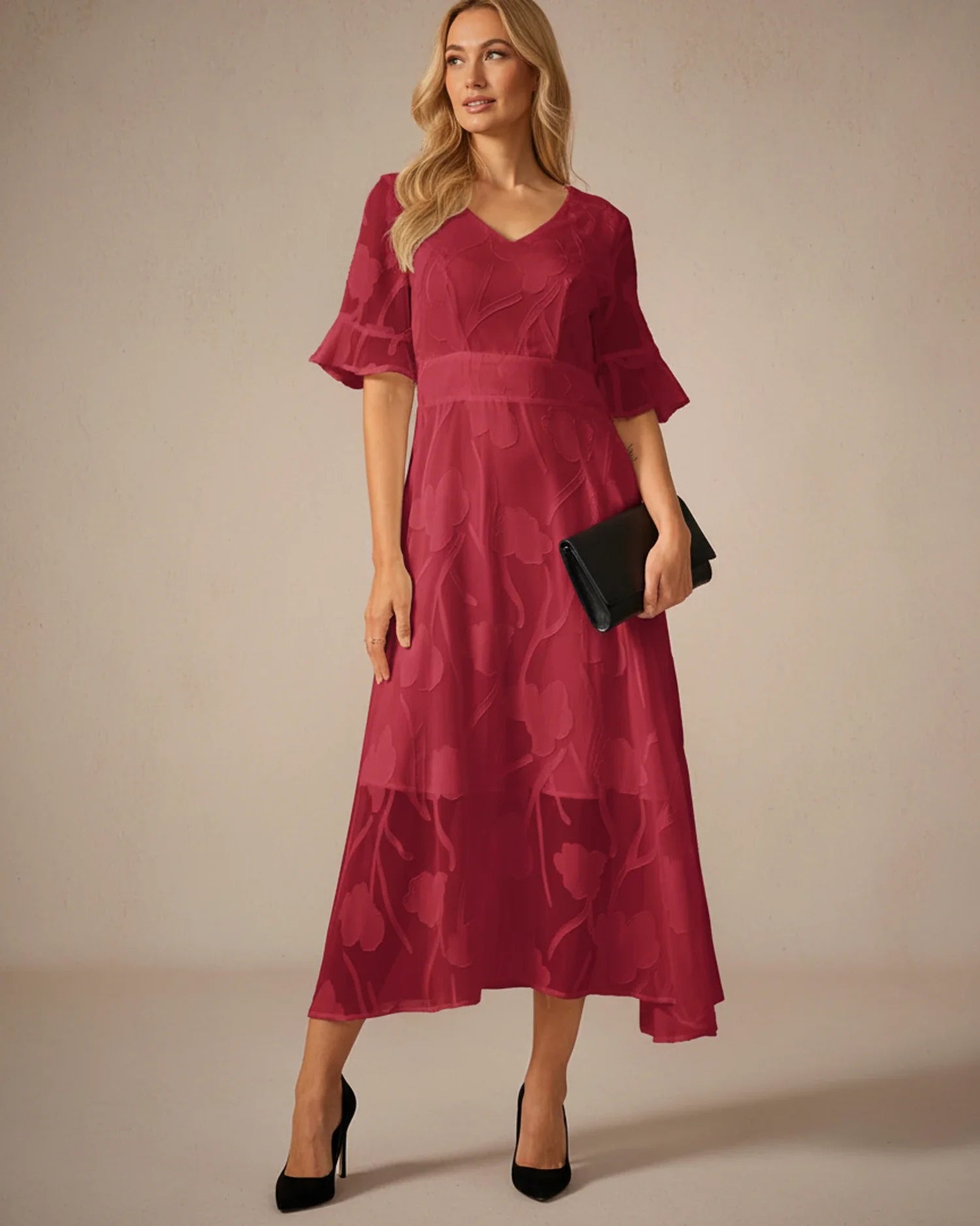 Red - A woman models a black formal midi dress featuring a V-neckline, flutter sleeves, and a textured floral jacquard overlay with a sheer hemline.