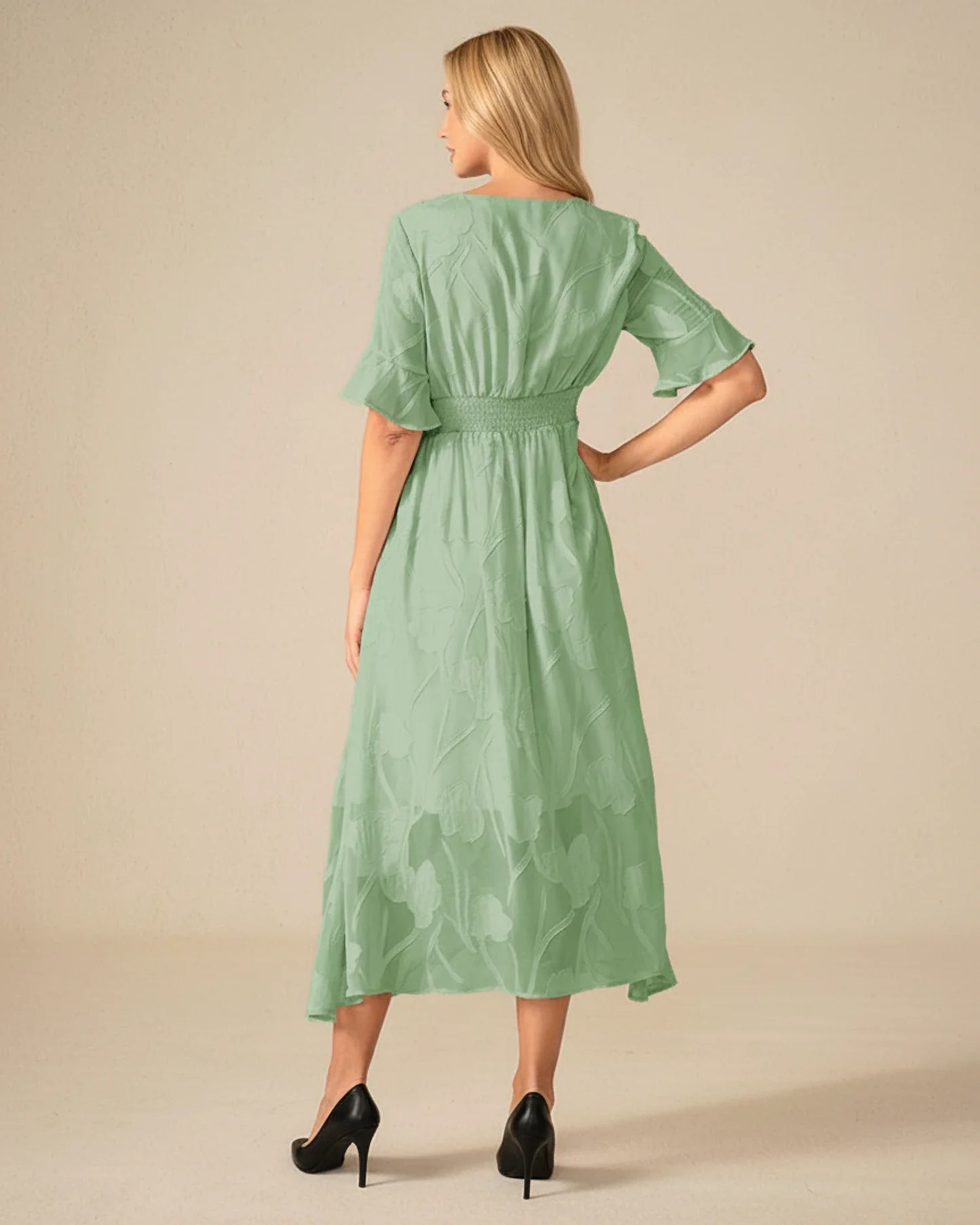 Green - A woman models a black formal midi dress featuring a V-neckline, flutter sleeves, and a textured floral jacquard overlay with a sheer hemline.