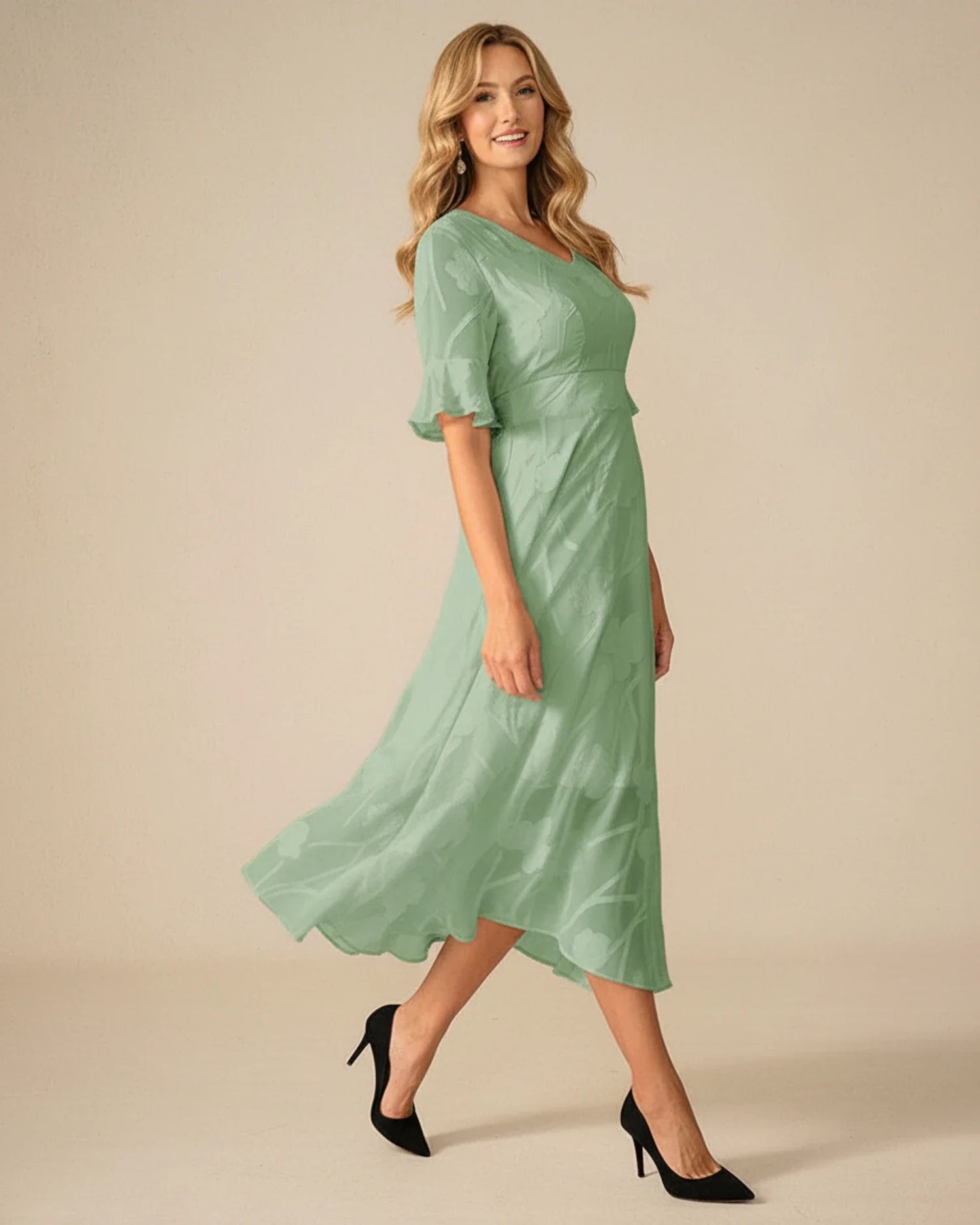 Green - A woman models a black formal midi dress featuring a V-neckline, flutter sleeves, and a textured floral jacquard overlay with a sheer hemline.