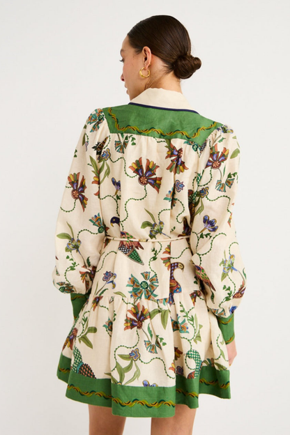 Green - Woman wearing a floral print long-sleeve mini dress with a collared neckline, covered buttons, and a tiered skirt against a plain background.