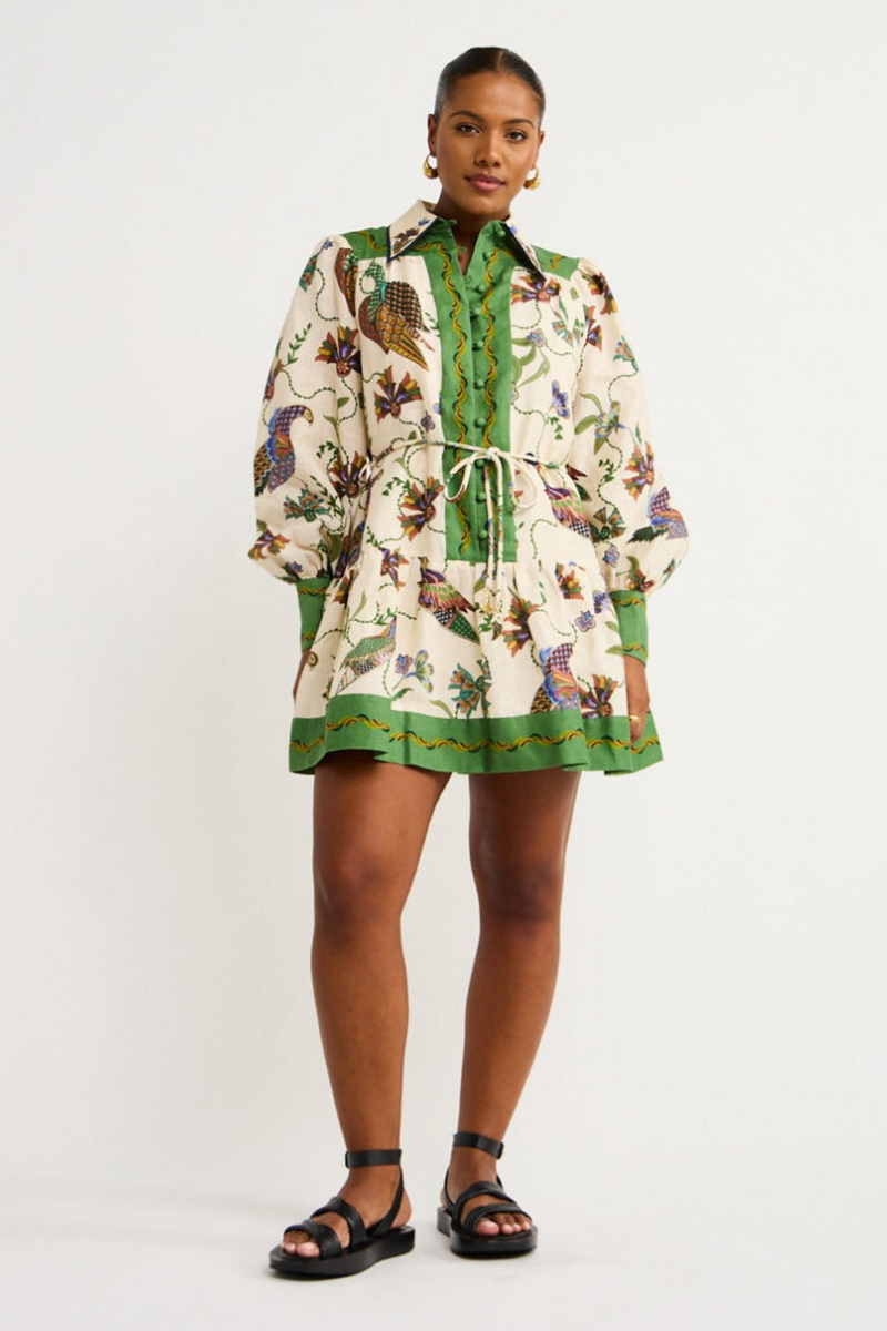 Green - Woman wearing a floral print long-sleeve mini dress with a collared neckline, covered buttons, and a tiered skirt against a plain background.