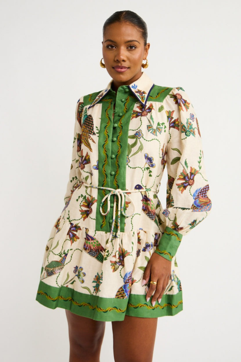 Green - Woman wearing a floral print long-sleeve mini dress with a collared neckline, covered buttons, and a tiered skirt against a plain background.