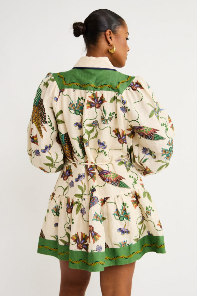 Green - Woman wearing a floral print long-sleeve mini dress with a collared neckline, covered buttons, and a tiered skirt against a plain background.