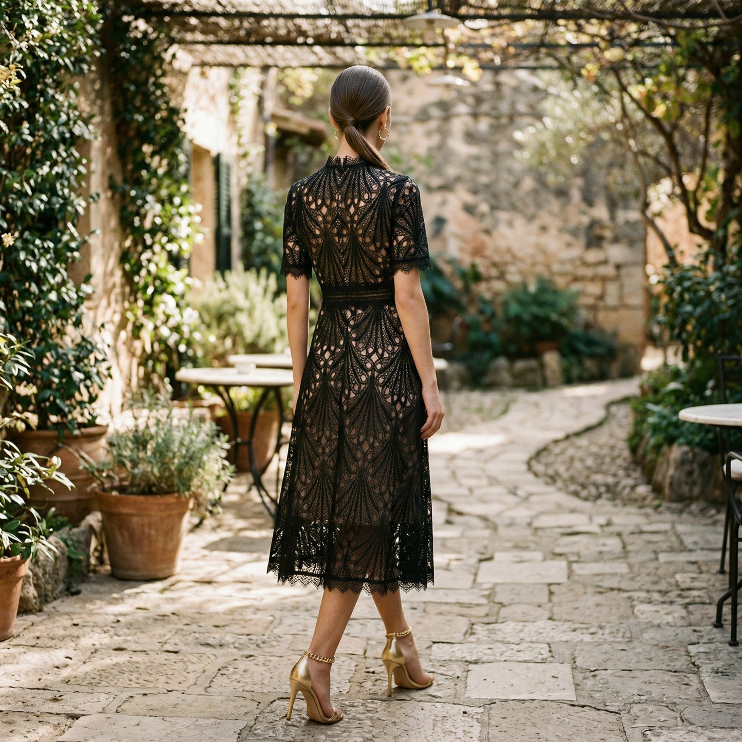 Black - A woman wearing a black geometric lace midi dress with a high neck, short sleeves, and a defined waist, featuring a nude lining and scalloped hem.