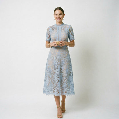 Light Blue - A woman wearing a black geometric lace midi dress with a high neck, short sleeves, and a defined waist, featuring a nude lining and scalloped hem.