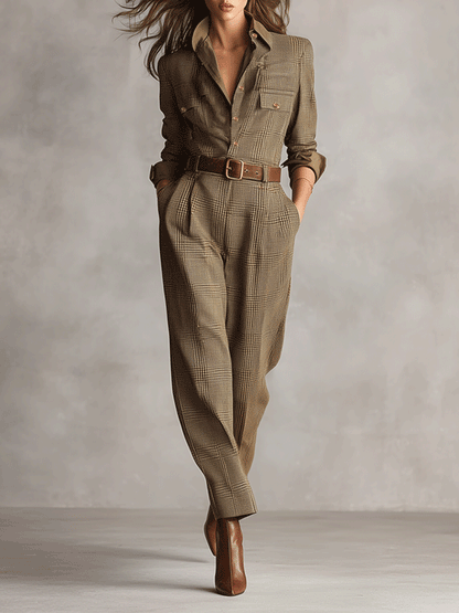 Brown - A woman wearing a tailored, long-sleeve glen plaid jumpsuit in olive and brown tones, featuring a point collar, button-front closure, utility pockets, and pleated tapered trousers cinched with a brown leather belt.