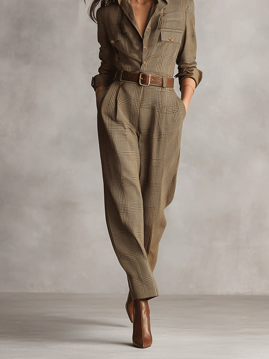 Brown - A woman wearing a tailored, long-sleeve glen plaid jumpsuit in olive and brown tones, featuring a point collar, button-front closure, utility pockets, and pleated tapered trousers cinched with a brown leather belt.